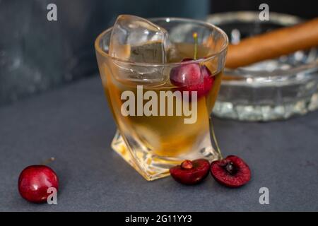 Un whisky de cerise noir fin dans un verre rocailleux inhabituel avec un fond d'ardoise gris. Banque D'Images