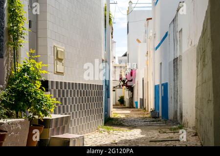 Rue étroite avec des maisons blanches et des fleurs à Olhao, Algarve, Portugal Banque D'Images