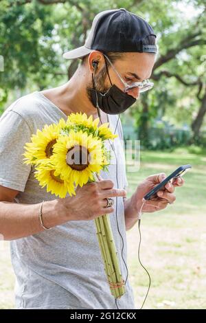 Miami Florida, Legion Park Farmers Market Day, homme hommes adultes, tenant des tournesols smartphone smartphones mobiles téléphone intelligent, textinin Banque D'Images