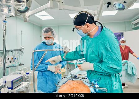 Une neurochirurgie esthétique qui travaille dur dans un hôpital professionnel. Chirurgien masculin travaillant en salle d'opération. Banque D'Images