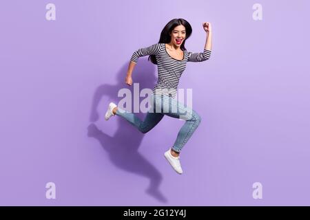 Pleine taille profil photo de côté de heureux funky sourire gai coréenne fille courir rapidement dans l'air isolé sur fond violet couleur Banque D'Images