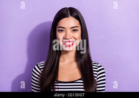 Photo de jeune belle beaming charmante fille asiatique avec rouge à lèvres porter chandail rayé isolé sur fond violet couleur Banque D'Images