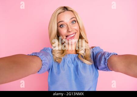 Photo de jeune heureux souriant funky drôle positive fille prenant selfie montrant la langue isolée sur fond rose couleur Banque D'Images