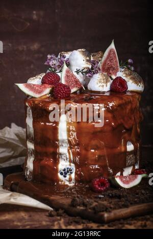 Gâteau au caramel avec baies sauvages, crème et figues sur fond marron Banque D'Images