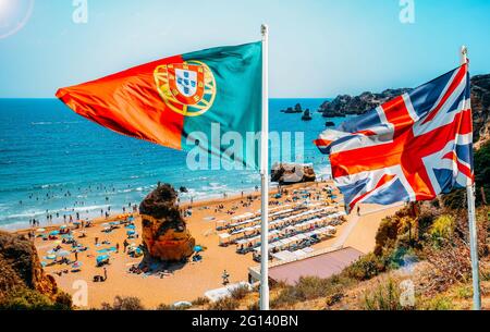 Le Portugal et le Royaume-Uni drapeau en premier plan avec vue sur les plages de Cova Redonda Beach en Algarve, dans le sud du Portugal Banque D'Images