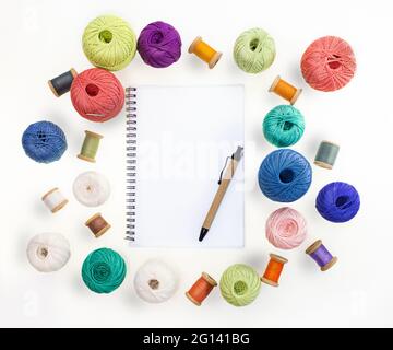 Boules multicolores et bobines de fils de laine, manchons de fils de bois sur fond blanc isolé. Bloc-notes avec stylet. Travaux d'aiguille faits à la main. Vue de a Banque D'Images