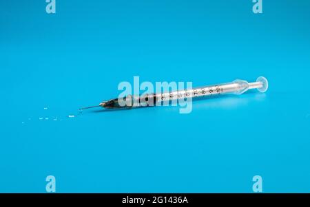 Seringue d'insuline médicale avec gouttes de médicament, aiguille pointue, sur fond bleu vif. Placer pour le texte. Photographie macro. Photo de la pandémie de Covid, Banque D'Images