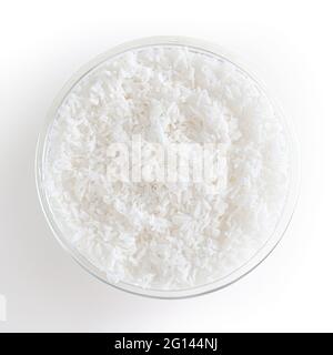 Flocons de noix de coco dans un bol en verre isolé sur fond blanc avec passe-cheveux Banque D'Images