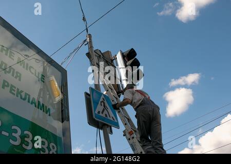 Dnepropetrovsk, Ukraine - 05.30.2021: Les travailleurs des services publics de la ville peinent un feu de circulation. Un employé effectue un travail dangereux pendant Banque D'Images