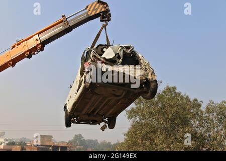 Une grue soulève une voiture brisée pour la charger sur un camion de remorquage sur le lieu de l'accident. Haryana, Inde Banque D'Images