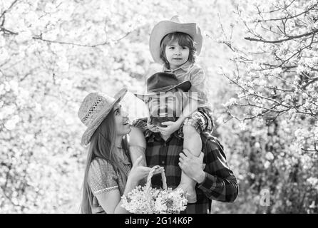 Fermiers dans le jardin en fleur. Parents qui grandissent petit bébé. Passez du temps ensemble. Belle famille à l'extérieur nature arrière-plan. Concept Ranch. Bonne famille Banque D'Images