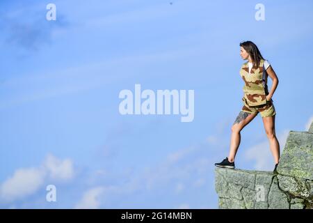 La femme courageuse est seule dans les hautes montagnes bleu ciel fond. Concept de dépression. Fille soldat. Militaire femme. Point d'observation. Fille courageuse Banque D'Images