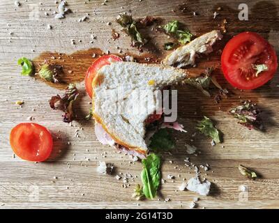 Un demi-sandwich de salade de jambon mangé dans un concept de déchets alimentaires Banque D'Images