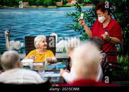 03 juin 2021, Brandenburg, Neuruppin: La résidente Johanna Muschel (retour, l) regarde Marion Wodetzki (r), soignant, tenant une carte de bingo pendant un tournoi de bingo à la maison des seniors de l'ASB à Neuruppin. Johanna Muschel, 94 ans, vit dans la maison des seniors 'Am Schulplatz', dirigée par l'Arbeiter-Samariter-Bund (ASB), sur la place du marché. À l'installation, elle peut également poursuivre son passe-temps dans un groupe. « J'aime bien m'entraîner, devinez », explique la dame très animée. Dans les maisons, la vie quotidienne normale est lentement de retour avec les chiffres de l'infection de Corona en baisse et les résidences vaccinées Banque D'Images