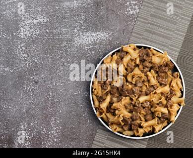 Pâtes en sauce crémeuse avec foie de poulet sur une assiette ronde sur fond sombre. Vue de dessus, plan d'appartement Banque D'Images