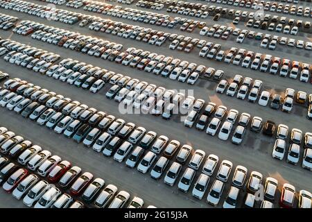 Vue aérienne de nouvelles voitures alignées dans le parking pour l'importation et l'exportation logistique d'affaires à la concession pour la vente, automobile et voiture par Banque D'Images