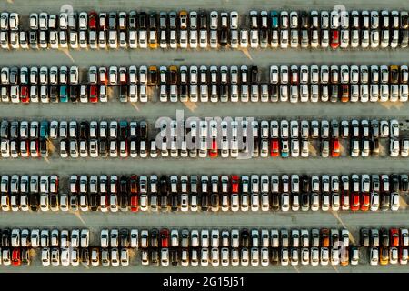 Vue aérienne de nouvelles voitures alignées dans le parking pour l'importation et l'exportation logistique d'affaires à la concession pour la vente, automobile et voiture par Banque D'Images