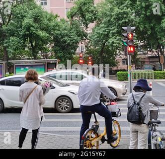 Pékin, Chine. 19 mai 2021. Photo prise avec un téléphone portable montre les gens qui attendent de traverser une rue pendant la soirée heure de pointe à Beijing, capitale de la Chine, le 19 mai 2021. Selon un rapport publié à la fin de 2020 par l'Académie chinoise de planification et de conception urbaine et Baidu Map, le temps moyen de trajet aller-simple des navetteurs de Pékin est de 47 minutes, Et la distance moyenne pour le trajet aller simple est de 11.1 km. Cinquante-huit pour cent des navetteurs passent en 45 minutes, et 26 % d'entre eux passent plus de 60 minutes. Credit: Ding Hongfa/Xinhua/Alamy Live News Banque D'Images