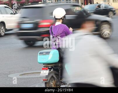 Pékin, Chine. 12 mai 2021. Photo prise avec un téléphone portable montre une femme attendant de traverser une rue pendant la soirée heure de pointe à Beijing, capitale de la Chine, le 12 mai 2021. Selon un rapport publié à la fin de 2020 par l'Académie chinoise de planification et de conception urbaine et Baidu Map, le temps moyen de trajet aller-simple des navetteurs de Pékin est de 47 minutes, Et la distance moyenne pour le trajet aller simple est de 11.1 km. Cinquante-huit pour cent des navetteurs passent en 45 minutes, et 26 % d'entre eux passent plus de 60 minutes. Credit: Ding Hongfa/Xinhua/Alamy Live News Banque D'Images