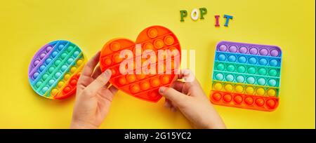 Les enfants jouent avec le jouet pop IT fidget coloré. Jouet sensoriel antistress coloré, le violon pousse-le. Banque D'Images