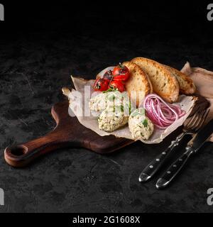 Plat classique de cuisine israélienne - forshmak de hareng légèrement salé. Servi avec une ciabatta croustillante et des oignons marinés sur fond sombre. Mise au point sélective Banque D'Images