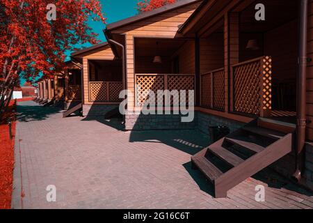 Un cliché infrarouge d'un groupe de maisons en bois similaires d'une auberge de jeunesse ou d'un camping avec des vérandas et de petits escaliers menant à des stoops; une pierre de pavage Banque D'Images