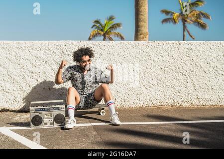 Jeune Afro Latin homme ayant l'amusement dansant tout en écoutant de la musique avec des écouteurs et boombox vintage pendant les vacances d'été Banque D'Images