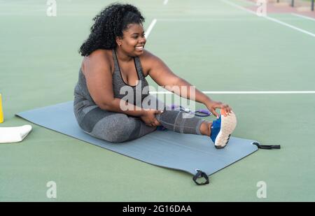 Curvy Afro femme faisant des exercices d'étirement session - Jeune africaine femme ayant l'entraînement amusant en plein air - Sporty People style de vie concept Banque D'Images