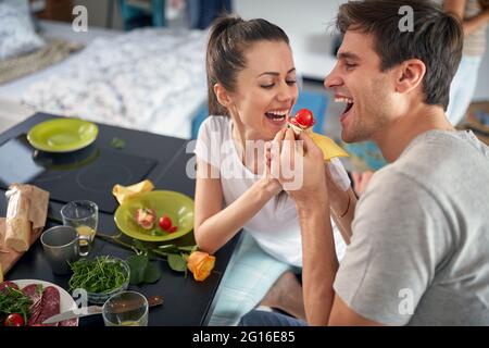 Un jeune couple aime se nourrir les uns les autres tout en prenant un petit déjeuner dans une atmosphère gaie à la maison. Amour, ensemble, petit déjeuner, maison Banque D'Images