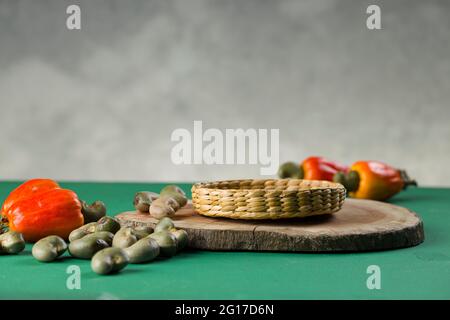 Pomme de noix de cajou et graines de noix de cajou disposées sur une base verte texturée avec fond gris, foyer sélectif Banque D'Images