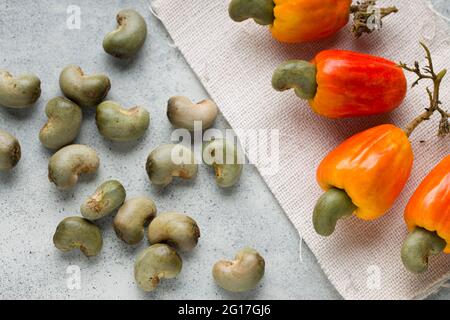 La pomme de cajou et les graines de cajou sont placées sur fond texturé gris, vue du dessus. Banque D'Images