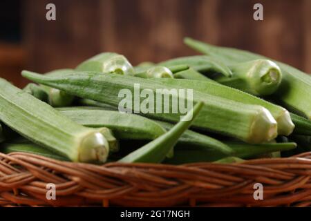 Okra ou Lady's Finger ou Bhindi légume vert frais disposé dans un panier avec un fond en bois texturé, isolé et sélectif foyer Banque D'Images