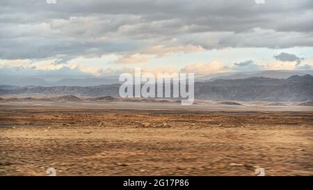 Paysage typique à la frontière entre Israël et la Jordanie, vu depuis la conduite en voiture sur la Highway 90. Désert plat et sec avec de petites montagnes du côté jordanien, le soleil brille t Banque D'Images