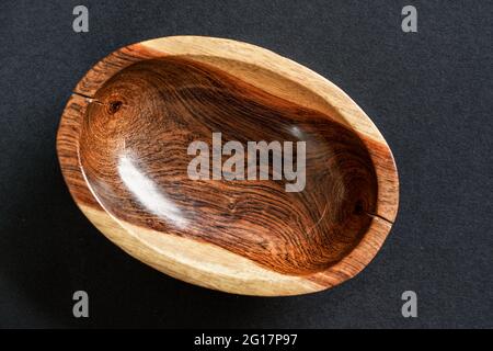 Petit bol en bois de rose poli sur table noire, vue rapprochée du dessus Banque D'Images