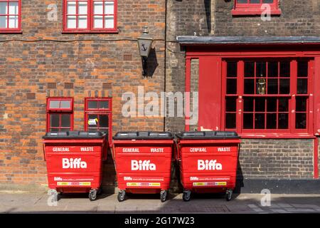 3 grandes boîtes de Biffa rouges contre un mur de briques avec des fenêtres rouges. Londres - 5 juin 2021 Banque D'Images