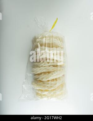 Krupuk ou Kerupuk, craquelins traditionnels indonésiens, placés en plastique transparent sur fond blanc. Banque D'Images