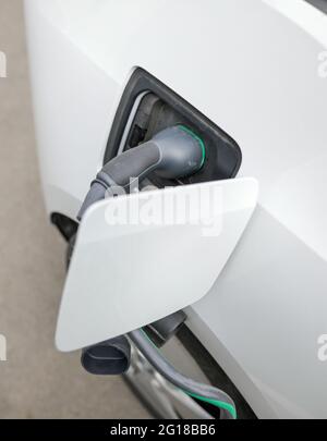 Image de faible profondeur de champ (mise au point sélective) avec un câble de chargement de voiture électrique et une prise sur une station de charge. Banque D'Images
