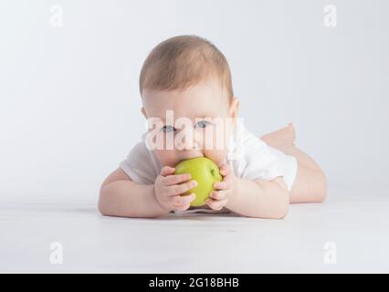 mignon bébé mangeant de la pomme verte, sur fond blanc Banque D'Images