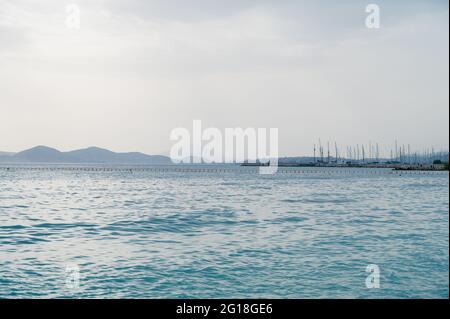 Magnifique paysage de la mer Égée à Athènes par temps nuageux. Silhouettes d'îles dans la brume. Voiles yachts près de la jetée. Banque D'Images