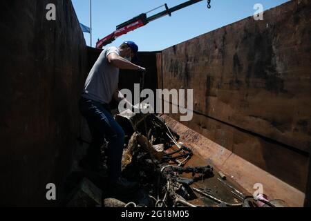 Rafina, Grèce. 5 juin 2021. Un volontaire dépose les déchets dans une poubelle métallique au port de Rafina, à environ 30 km à l'est d'Athènes, en Grèce, le 5 juin 2021. La Grèce met en avant la pollution par les plastiques marins, qui marque la Journée mondiale de l'environnement, qui tombe le 5 juin, et la Journée mondiale des océans le 8 juin, avec le lancement par le ministère de la navigation d'un projet de nettoyage de huit ports grecs. Credit: Lefteris Partsalis/Xinhua/Alamy Live News Banque D'Images