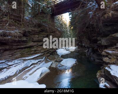 Ruisseau gelé d'hiver qui coule sous le petit pont de Natural Stone Arch dans Deep Valley. Montagnes des Carpates, Ukraine Banque D'Images