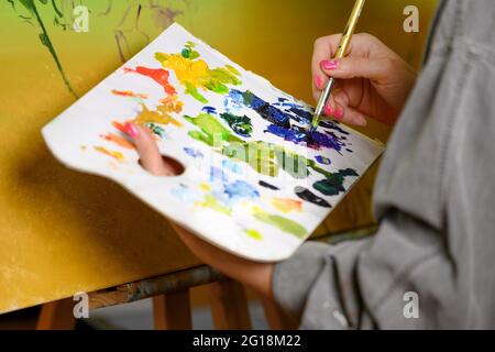 Femme artiste mélange des peintures sur la palette, peintre au studio, créateur fait des œuvres d'art photo de haute qualité Banque D'Images