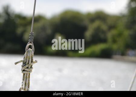 Détail de la fixation sur un bateau à voile : corde attachée dans un nœud à travers une boucle sur un fil métallique (enveloppes : le côté reste sur un yacht). Arbres hors foyer et Banque D'Images