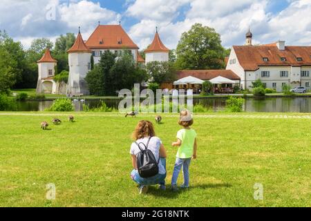 Les enfants se promène dans une prairie verte près du vieux château de Blutenburg, Munich, Bavière, Allemagne. Famille dans le parc de la ville en été. Cet endroit est une attraction touristique de Munic Banque D'Images