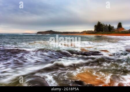 L'impressionnisme comme les pinceaux de vagues floues sur la plage de Mona Vale à Sydney au lever du soleil. Banque D'Images