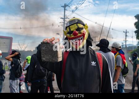 Un membre de la ligne de front utilisant un masque pose pour un portrait tenant un rocher pendant que des affrontements entre les manifestants et la police anti-émeute de Colombie (ESMAD) éclatent à Medellín, Colombie après plusieurs semaines de protestation anti-gouvernementale contre les réformes fiscales et sanitaires du Président Ivan Duque, les troubles et les abus de pouvoir qui ont fait au moins 70 morts selon les ONG le 4 juin 2021. Banque D'Images