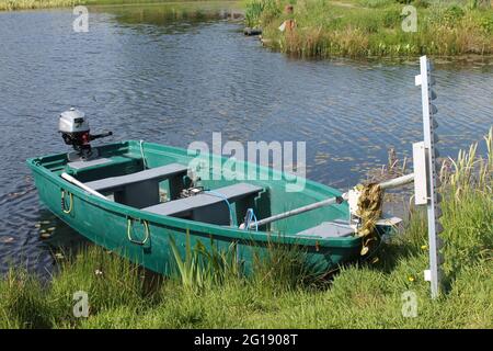 Bateau à moteur de pêche avec coupe-herbe fixé sur le bord d'un lac de pêche avec espace de copie Banque D'Images