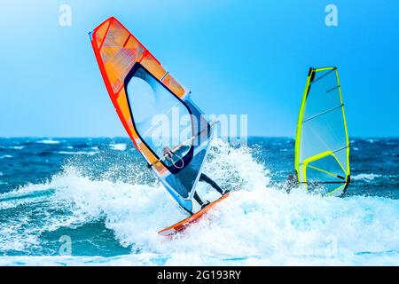 Sports aquatiques: Planches à voile sur une vague avec une voile orange sur l'océan Atlantique Banque D'Images