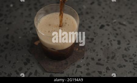 Verser le cola dans le verre à verre sur la glace sur le plan de travail en béton, photo large Banque D'Images