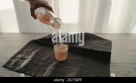 homme servant une boisson pétillante rose dans un verre à gobelet avec morceau de glace, grande photo Banque D'Images